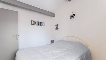 Une chambre à coucher avec un lit, une porte et un mur sur lequel est affiché un panneau indiquant « RELAX ».