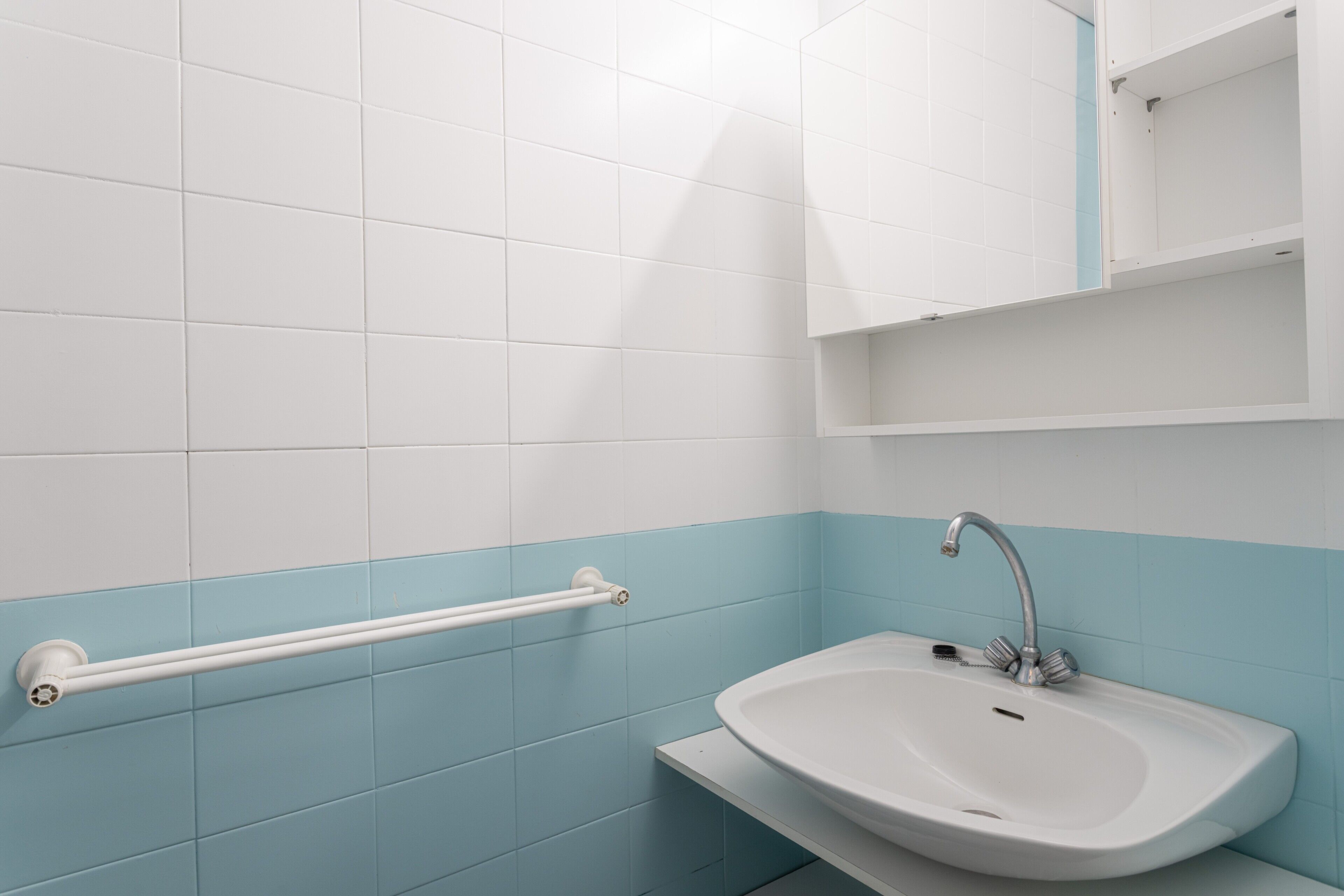 Une salle de bain avec un lavabo blanc, un porte-serviettes et un miroir.