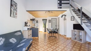 A compact living space with a sofa, dining table, kitchen area, and a staircase.