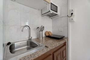A kitchen with a stainless steel sink, a microwave, and a toaster on the countertop.
