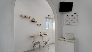 A small kitchen with a dining area, a TV mounted on the wall, and a window with blinds. - Apartment 'Candelaria C' with Wi-Fi (Valle Gran Rey)