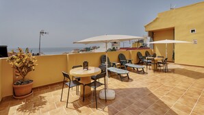 A terrace with a table and chairs, a potted plant, and a view of the sea. - Apartment 'Candelaria C' with Wi-Fi (Valle Gran Rey)