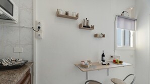A kitchen with a countertop, a microwave, a window with a blind, and two bar stools. - Apartment 'Candelaria C' with Wi-Fi (Valle Gran Rey)