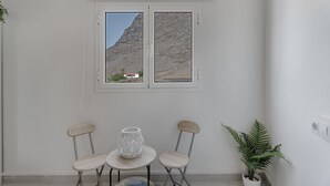A room with a window, two chairs, a small table, a potted plant, and a wall-mounted switch. - Apartment 'Candelaria C' with Wi-Fi (Valle Gran Rey)