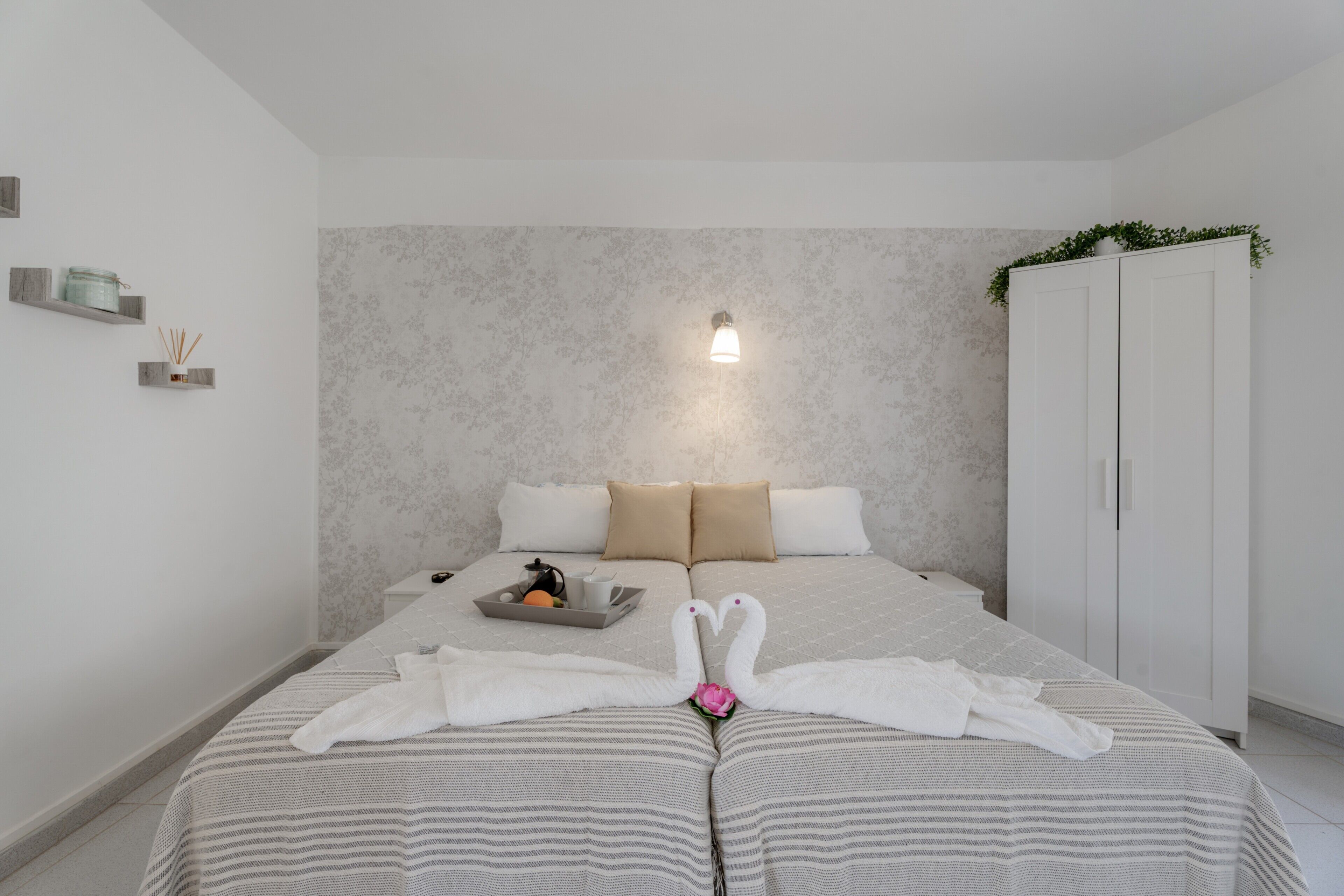 Ein Hotelzimmer mit Bett, Nachttisch, Kleiderschrank und Wandleuchte.
