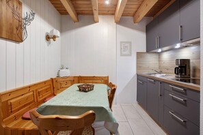 A dining area with a table, chairs, and a bench. There is a kitchen with cabinets and a coffee machine. - Apartment 4 with Shared Garden, Balcony and Wi-Fi (Todtmoos)