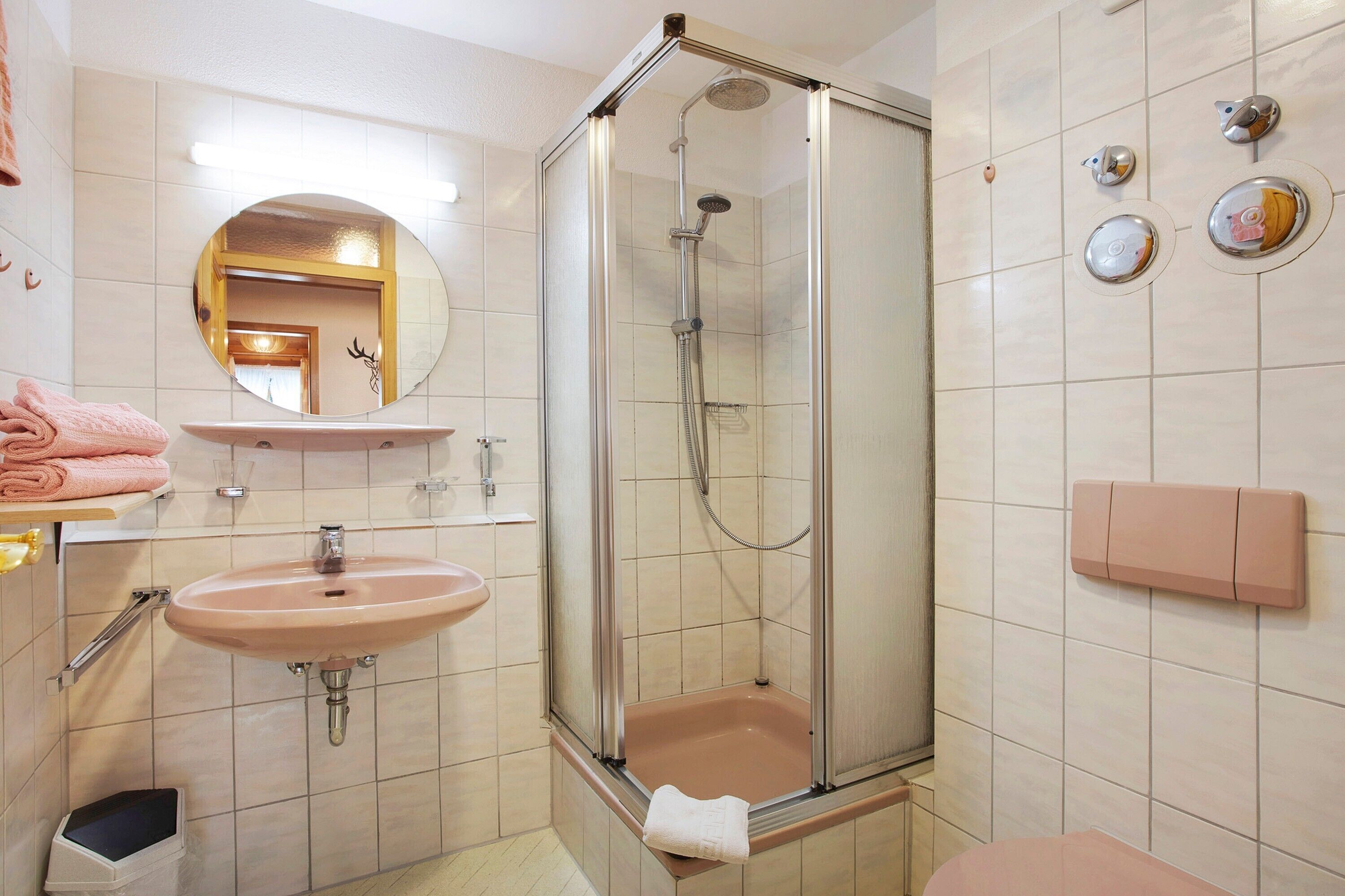 Un baño con ducha de vidrio, lavamanos y espejo.