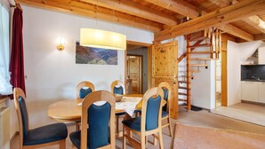 A wooden dining area with a table and chairs, a hanging light fixture, and a view of a mountain landscape. - Apartment 3 with Shared Garden, Balcony and Wi-Fi (Todtmoos)