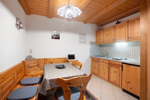 Una cocina compacta con armarios de madera, un salpicadero de azulejos y una mesa con bancos.