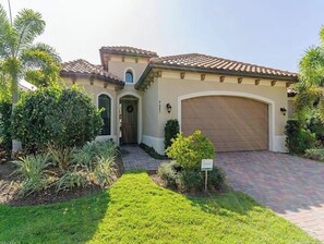 A residential house with a driveway, a garage, and a well-maintained lawn.