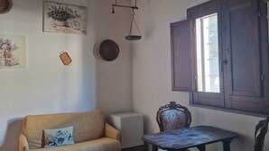 Une pièce chaleureuse avec un plafond en bois, un canapé, une table et une fenêtre dotée d’un volet en bois.