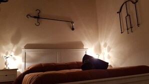 Une chambre à coucher comprenant un lit, une table de chevet et des lampes fixées au mur.