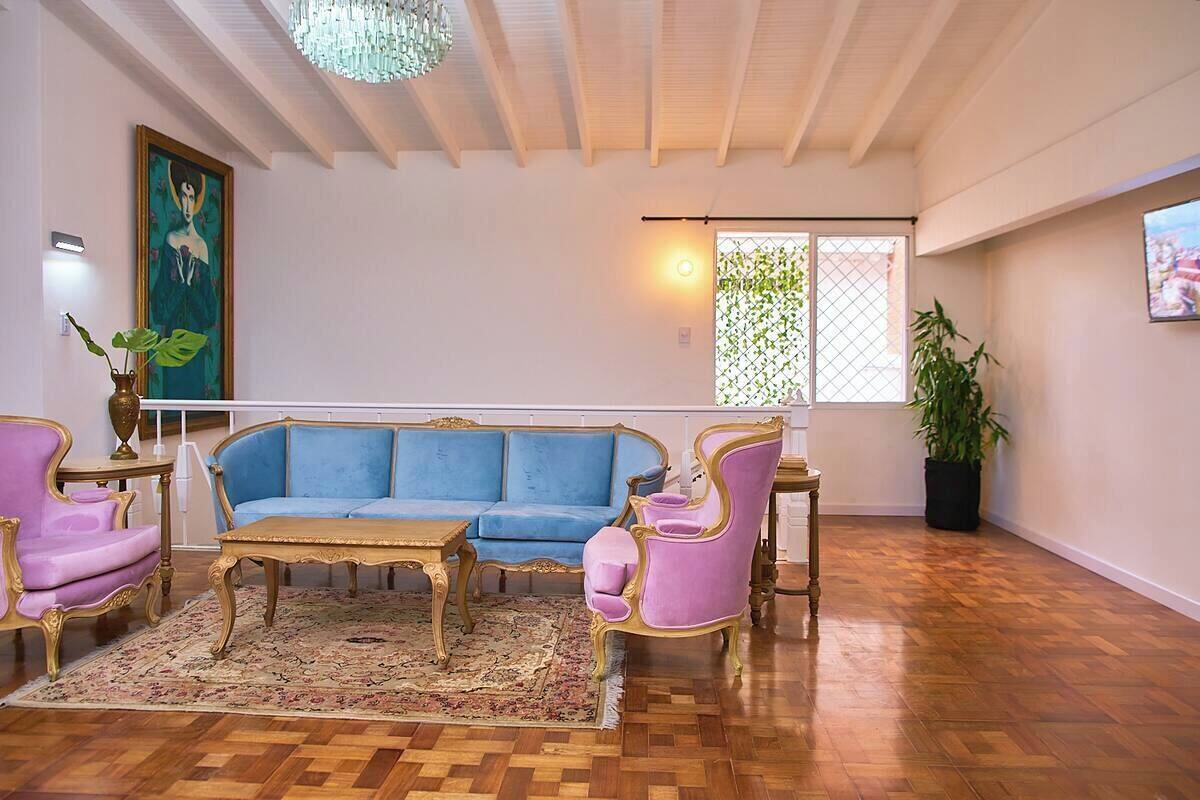 A spacious room with a blue sofa, pink armchairs, and a wooden coffee table.