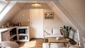 A cozy attic bedroom with a kitchenette, a sofa, a coffee table, and a potted plant. - Bali apartment with patio - Le Mans, apartment with patio - Le Mans (Le Mans)