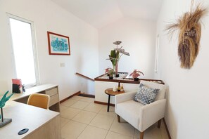 Un salon avec un canapé, une table basse, un bureau et une plante.