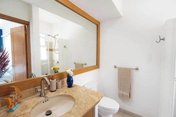 Une salle de bain équipée d’un lavabo, d’un miroir, de toilettes et d’un porte-serviettes.