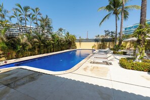 A swimming pool with a clear blue water, surrounded by palm trees and a building in the background. - Sleeps 10, Views & Beach 1 Block (Nuevo Vallarta)