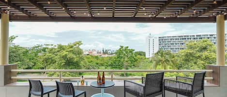 Ein Balkon mit vier Stühlen und einem Tisch, mit Blick auf eine Stadtlandschaft mit Grünflächen und Gebäuden.