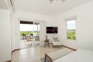 A modern hotel room with a bed, a TV mounted on the wall, a chair, and a view of the outdoors. - Sleeps 10, Views & Beach 1 Block (Nuevo Vallarta)