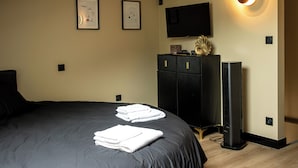 A bedroom with a skylight, a bed with neatly folded towels, a dresser, a TV, and a speaker.