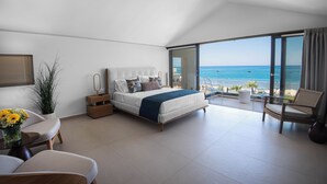 Ein modernes Schlafzimmer mit einem großen Bett, einer Sitzecke und einem Balkon mit Meerblick.