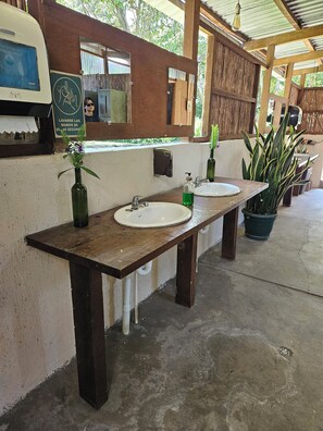 A restroom with two sinks, a mirror, and a soap dispenser.