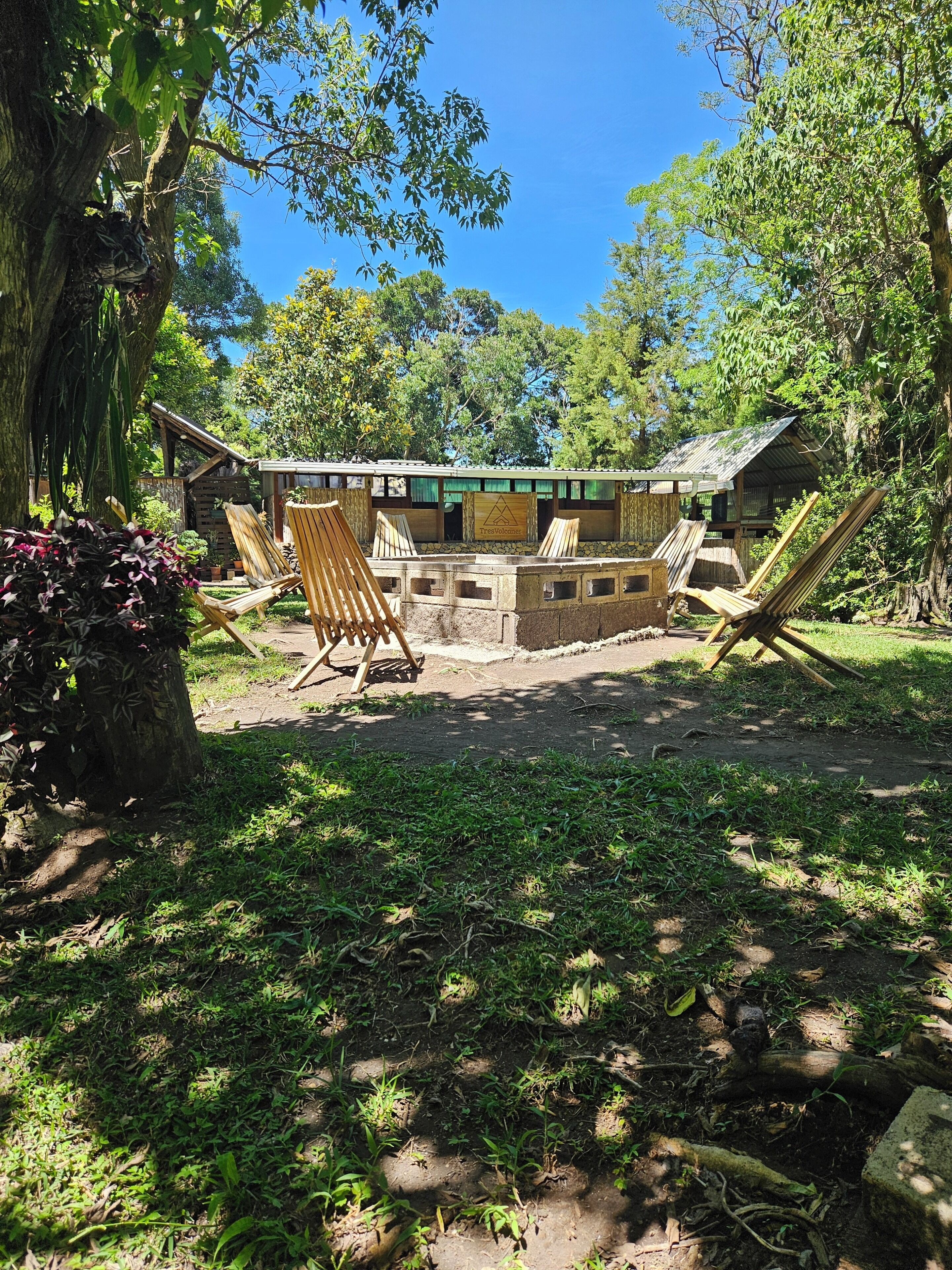 Un espacio de descanso rústico al aire libre con sillas de madera y una pequeña construcción de madera que dice 'TresVolcane'.