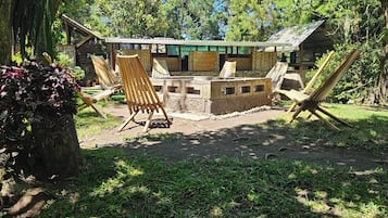 Un espacio de descanso rústico al aire libre con sillas de madera y una pequeña construcción de madera que dice 'TresVolcane'.