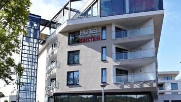 Un hôtel moderne à la façade en verre, nommé « Hôtel Amoreparco Einstein », qui comprend un restaurant-café situé au dernier étage.