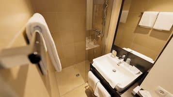 Une salle de bain moderne avec une douche à parois de verre, un lavabo avec un miroir et deux serviettes accrochées au mur.