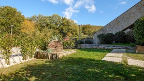 A garden with a stone wall, a wooden fence, and a paved pathway. - Terrazza Catabbio – Relax & Saturnia Thermal Baths – Garden and Pool (Catabbio)