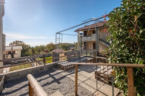 Una zona residencial con una estructura metálica, un banco de madera y un edificio con tejado de baldosas.