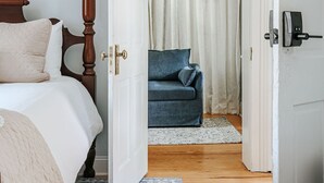 Et soveværelse med himmelseng, en blå sofa og en hvid dør, der fører til et andet rum.