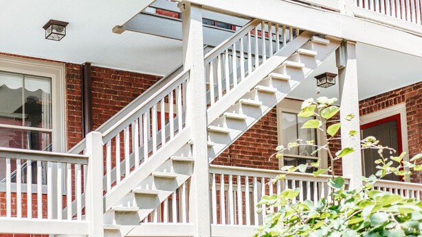 En boligbygning med en hvid trappe, der fører op til en balkon.