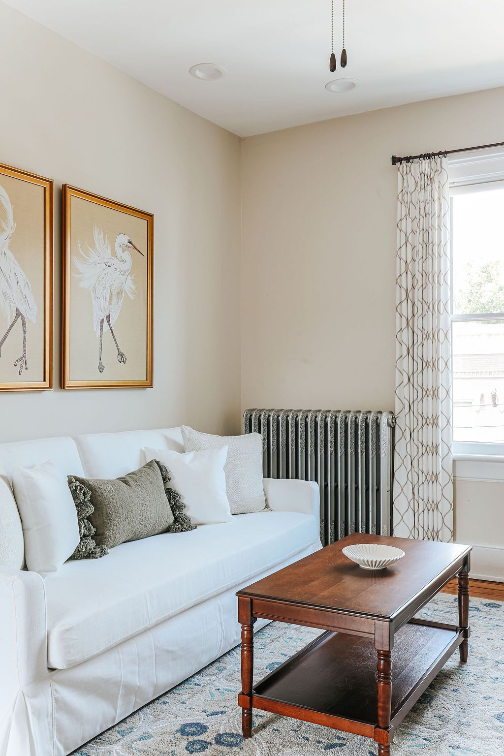 Ein Wohnzimmer mit einem weißen Sofa, einem Holztisch und zwei gerahmten Wandbildern.