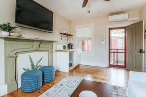 A living room with a fireplace, a television mounted on the wall, and a door leading outside.