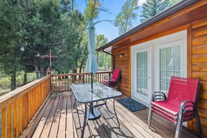 A wooden deck with a table and chairs, a covered umbrella, and a view of trees. - Hot Tub, Game Room, Mtn Views Near Ski & River (South Fork)