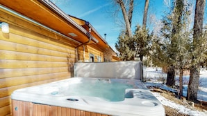 A wooden cabin with a hot tub in front of it.