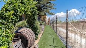 A pathway with artificial grass, a wooden barrel, and a metal fence. - 'Eco Del Mare' with veranda just steps from the sea (Pachino)