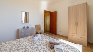 A bedroom with a bed, a dresser, a wardrobe, a mirror, and a chair. - 'Eco Del Mare' with veranda just steps from the sea (Pachino)