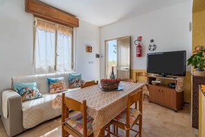 A cozy living room with a sofa, dining table, TV, and a fireplace. - 'Sea View' just steps from the sea (Pachino)