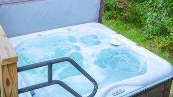 A hot tub with a wooden deck and a metal safety rail.