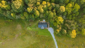 An aerial view of a property with a central building surrounded by dense greenery and a clear path leading to it.