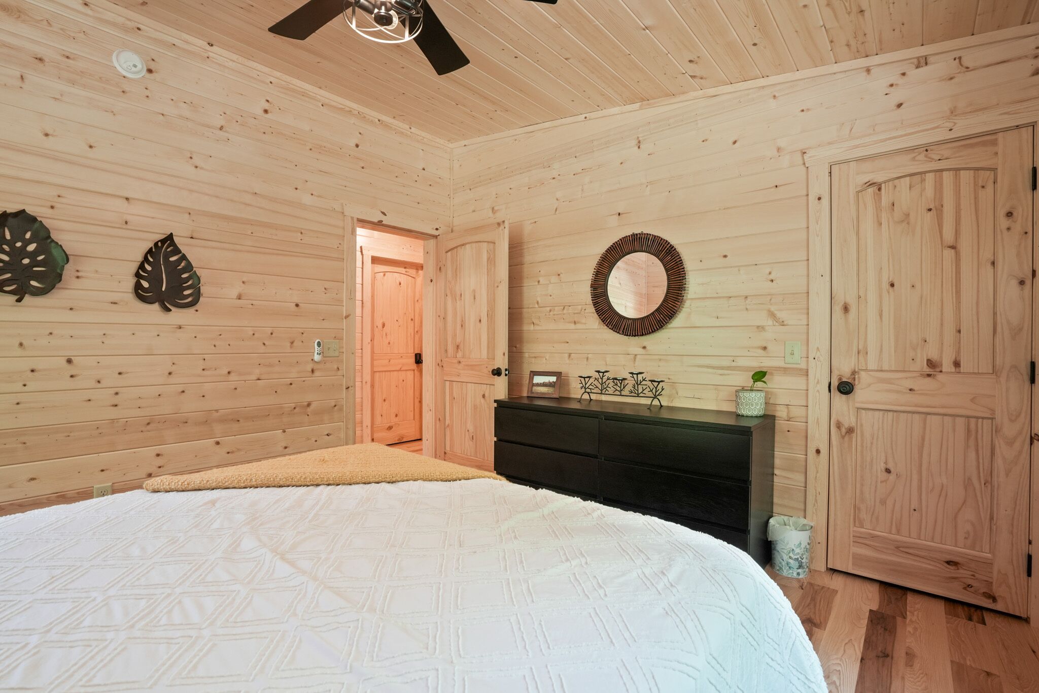 Un dormitorio con paneles de madera, una cama, un aparador y una puerta.