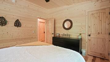 Un dormitorio con paneles de madera, una cama, un aparador y una puerta.