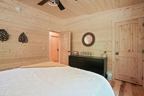 Une chambre aux murs lambrés, avec un lit, une commode et une porte.