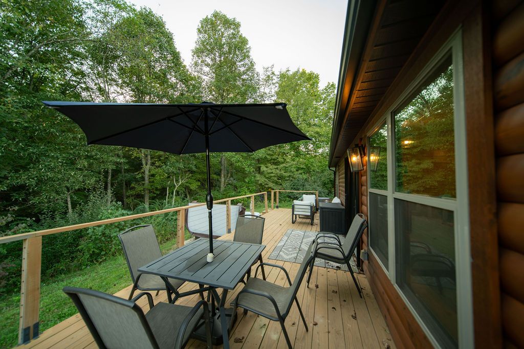 A wooden deck with outdoor furniture, including a table and chairs, and a large umbrella.