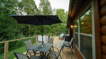 A wooden deck with outdoor furniture, including a table and chairs, and a large umbrella.