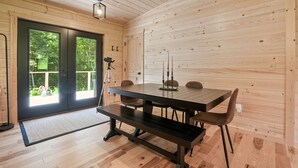 Un interior de madera con una mesa de comedor, bancos y una cámara sobre un trípode.