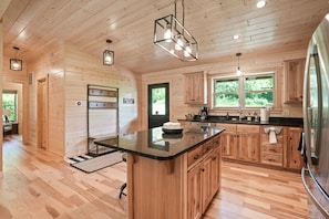 Une cuisine spacieuse avec des meubles en bois, un îlot central et un grand réfrigérateur.